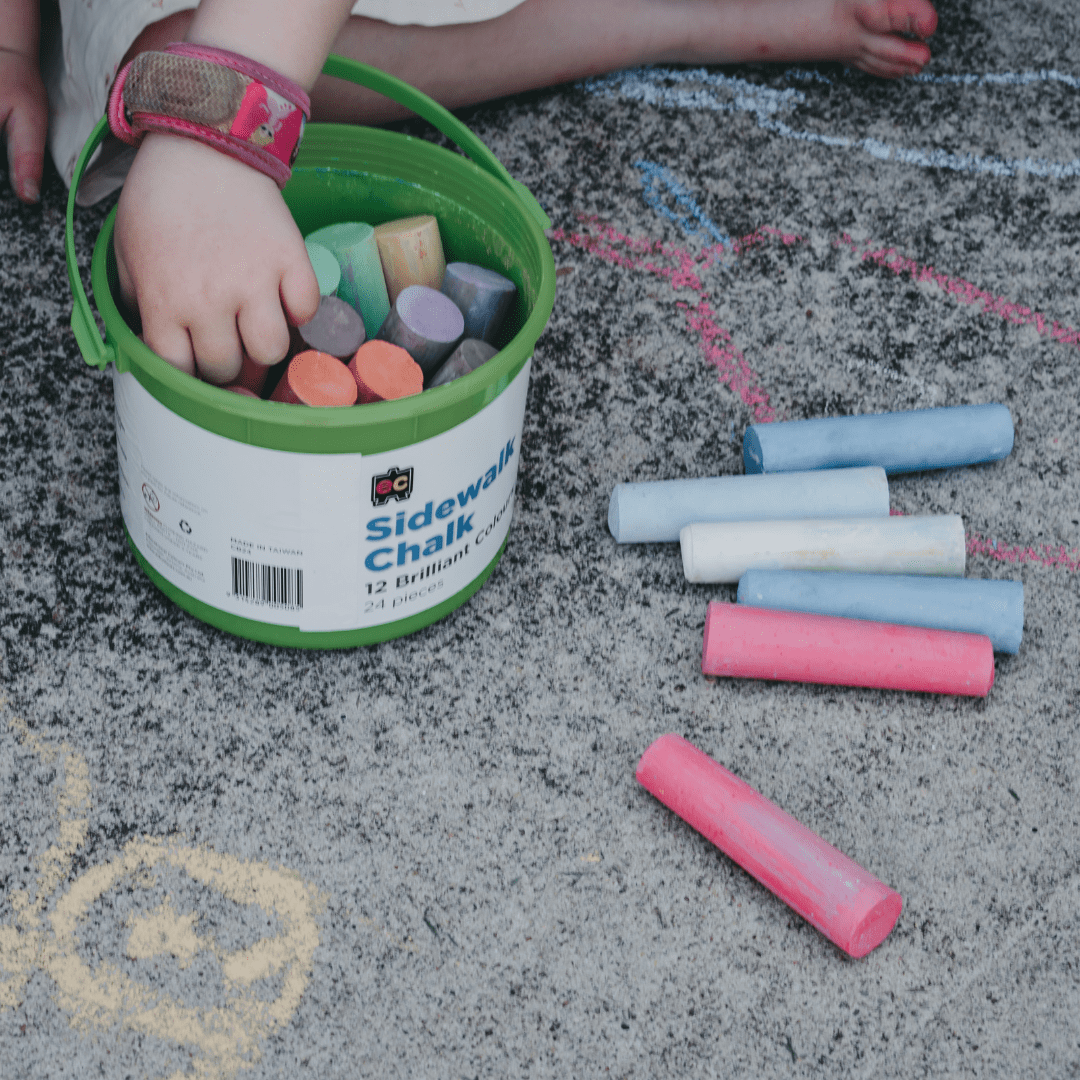 bucket with sidewalk chalk on the ground