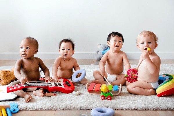 babys zitten naast elkaar op een rijtje met speelgoed instrumenten