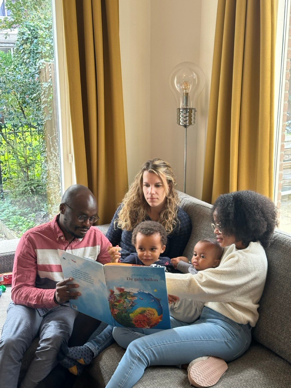 a family pointing something out in the book to a child